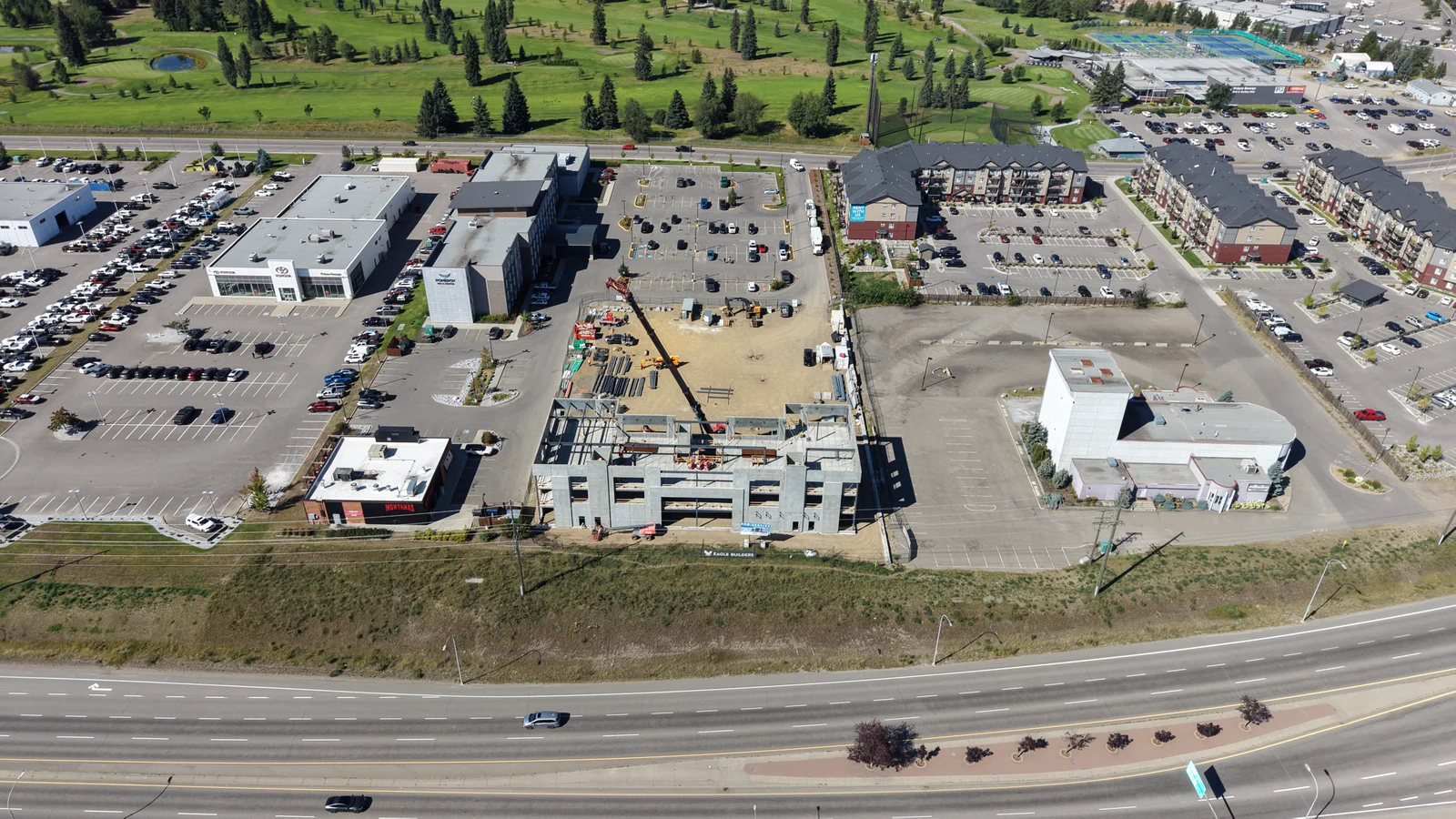 Wide aerial view of RECPLACE Professional Centre and its construction site beside Highway 16